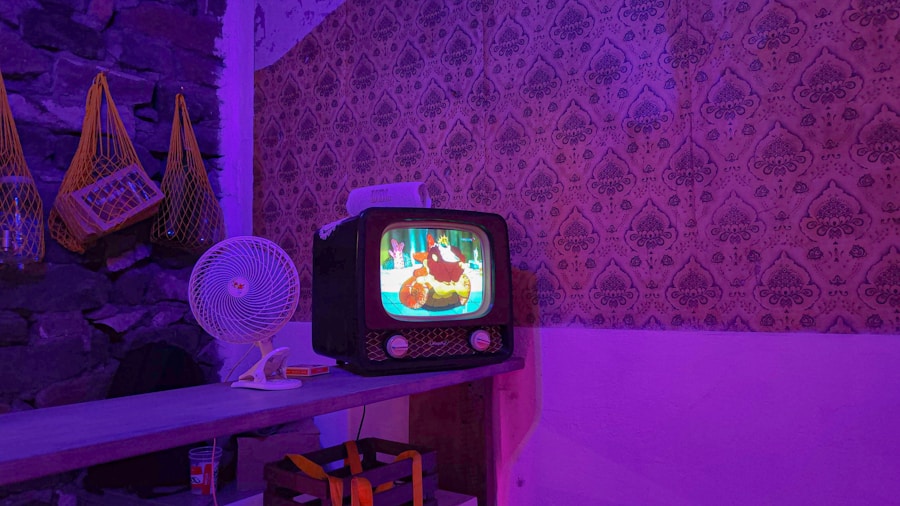 Un televisor antiguo muestra una caricatura en una habitación con papel tapiz estampado. Un pequeño ventilador se encuentra en un estante de madera al lado del televisor. La habitación está iluminada con luces violetas, lo que crea un ambiente acogedor y nostálgico.