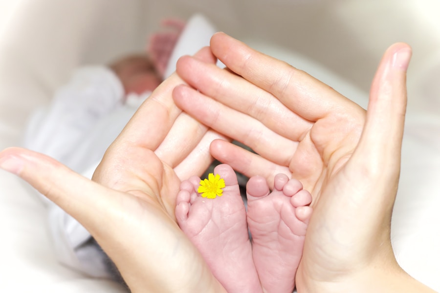 Primer plano de un par de manos de adultos que sostienen delicadamente los piececitos de un bebé. Una pequeña flor amarilla reposa sobre uno de los pies del bebé. El fondo está suavemente difuminado, lo que crea una atmósfera cálida y tierna.