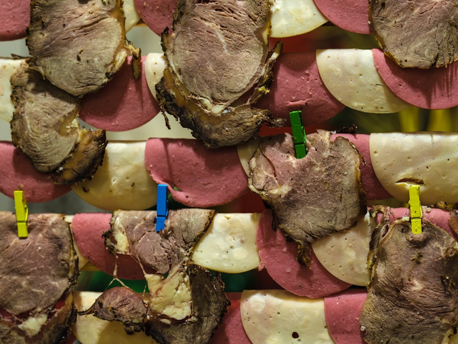 Las lonchas de embutido y queso están dispuestas en forma de tejido, con las piezas unidas por pequeñas pinzas de colores. Las carnes parecen incluir rosbif y mortadela.
